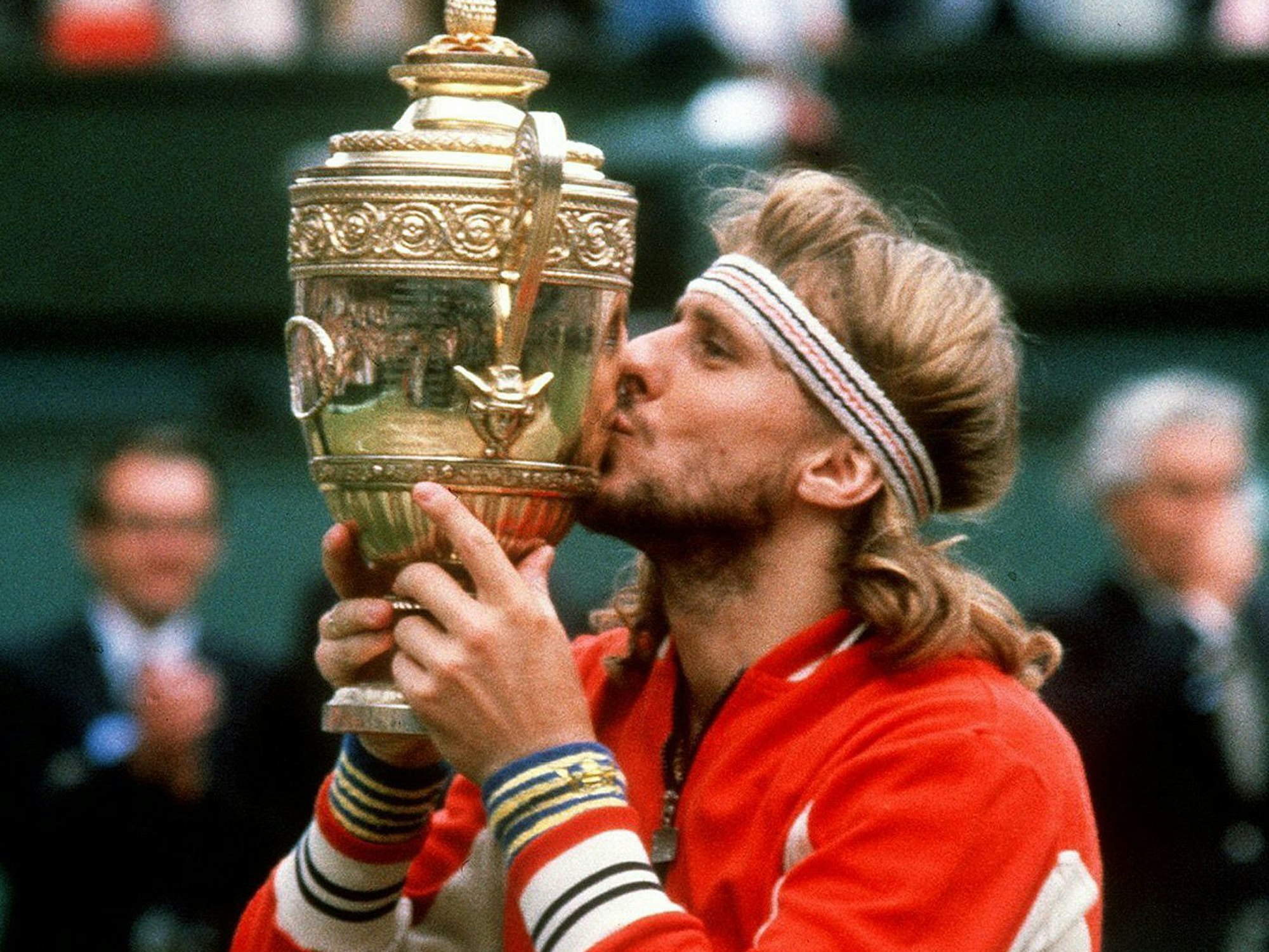 Björn Borg küsst die Wimbledon-Trophäe. Er trägt eine rote Trainingsjacke, ein gestreiftes Stirnband bändigt die langen Haare.
