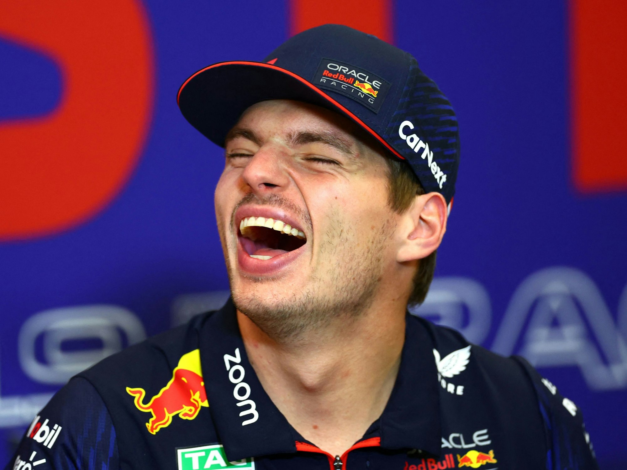 Max Verstappen lacht bei einer Pressekonferenz.