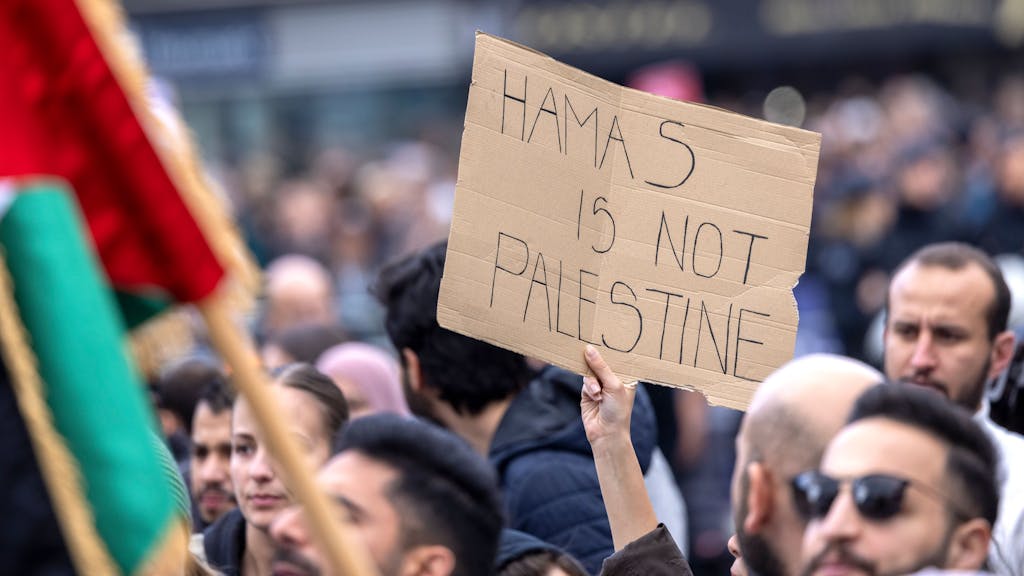 Ein Teilnehmer der Kundgebung hält ein Schild mit der Aufschrift „Hamas is not Palestine“ (Hamas ist nicht Palästina) hoch.&nbsp;