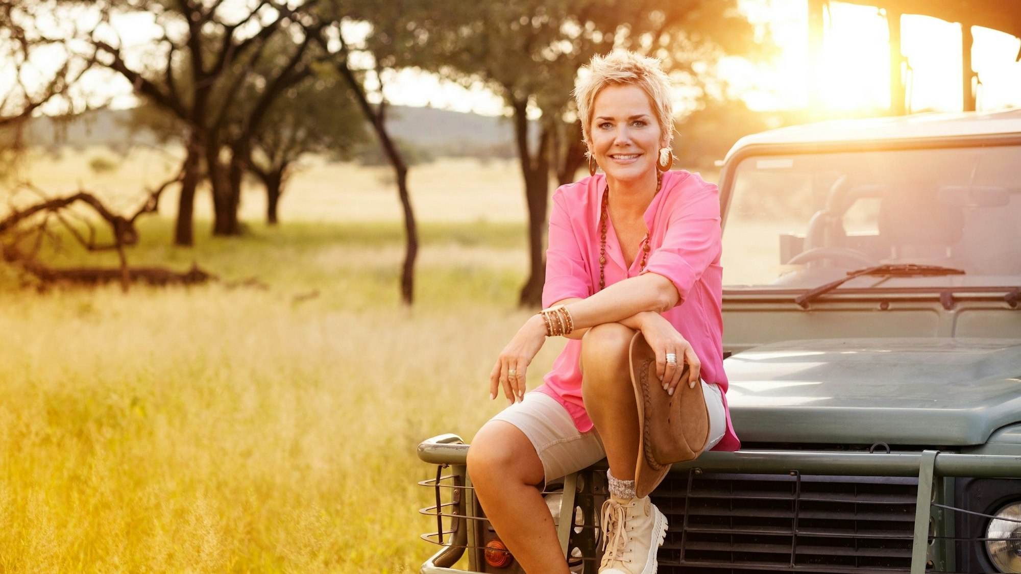 Das Foto zeigt die RTL-Moderatorin Inka Bause, die lächelnd auf der Motorhaube eines Autos sitzt. 