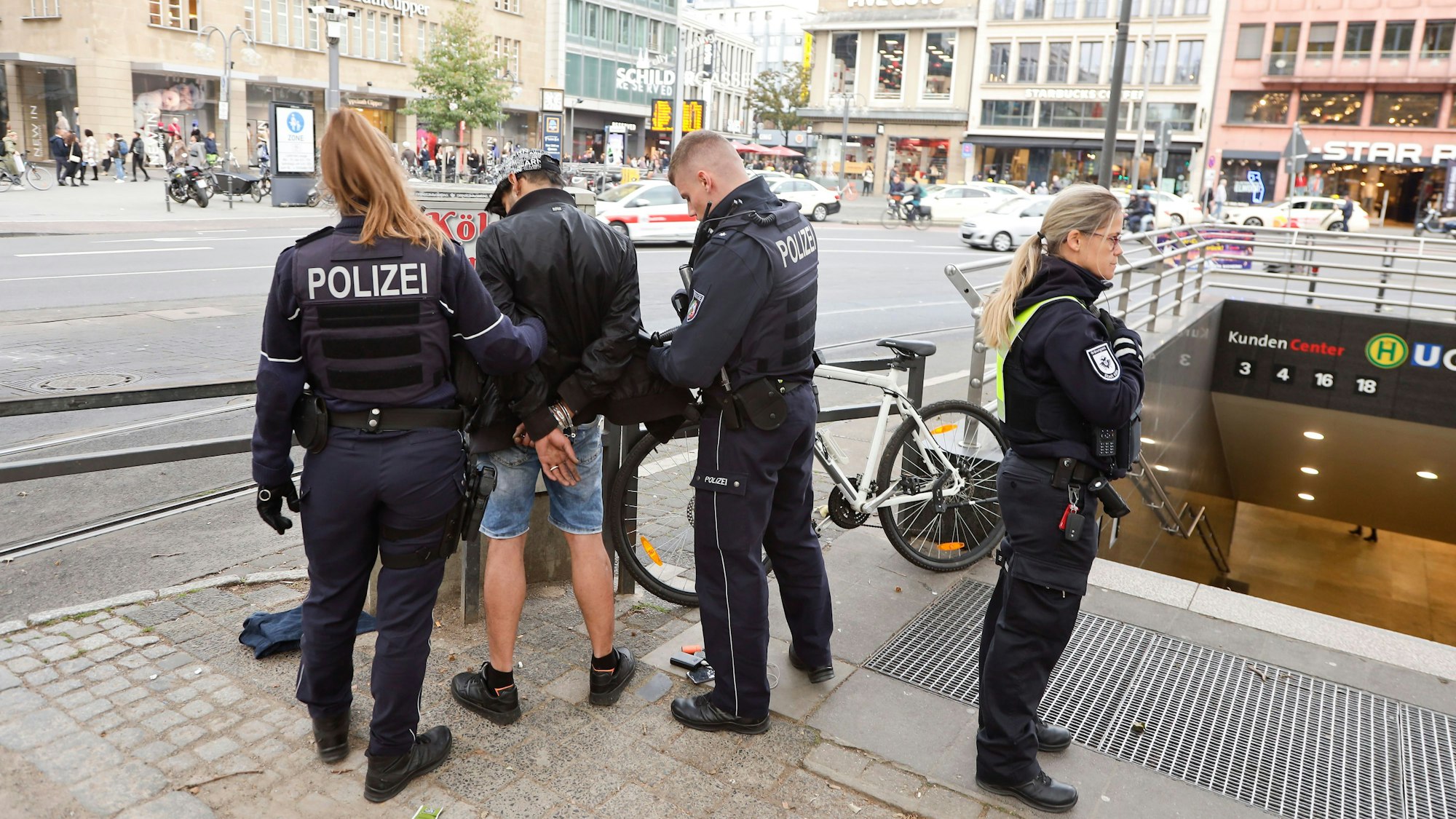 Polizisten und Ordnungsamt kontrollieren am Neumarkt in Köln einen Mann.