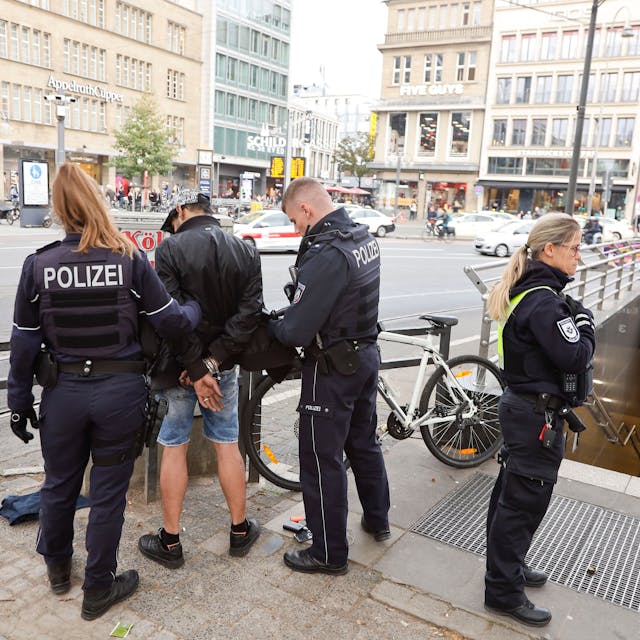 Polizisten und Ordnungsamt kontrollieren am Neumarkt in Köln einen Mann.
