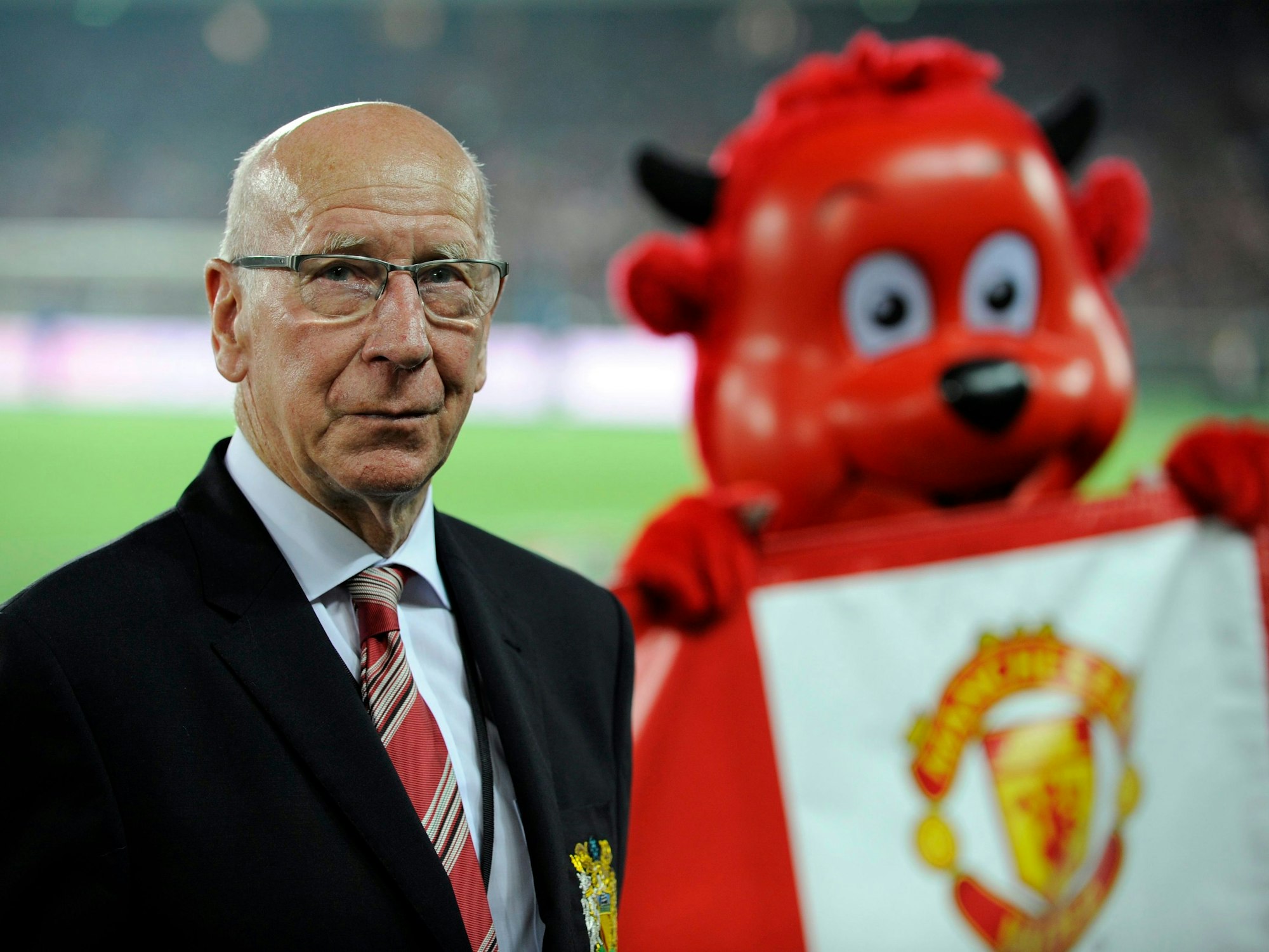 Sir Bobby Charlton posiert neben einem Maskottchen von Manchester United.