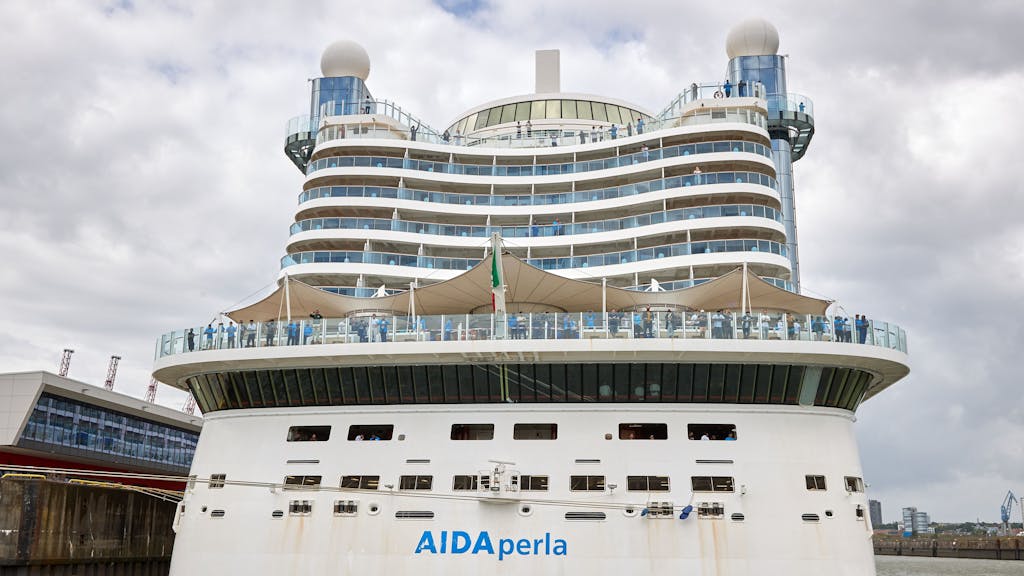 Besatzungsmitglieder des Kreuzfahrtschiffes AIDA perla freuen sich über ein Konzert, dass auf einem ihnen gegenüber liegenden Fahrgastschiff im Hamburger Hafen für sie gespielt wird.