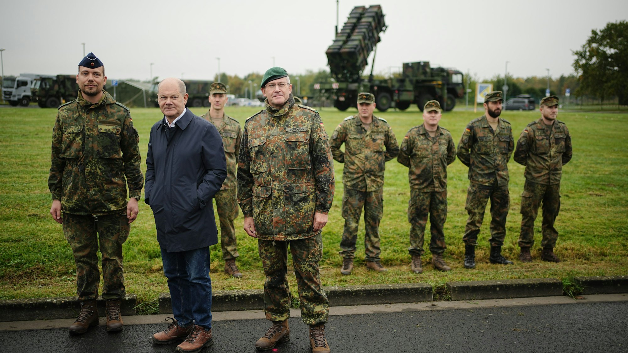 Bundeskanzler Olaf Scholz (SPD) steht zwischen Soldaten auf dem Militärflughafen Köln-Wahn vor einem Patriot-Flugabwehrsystem.