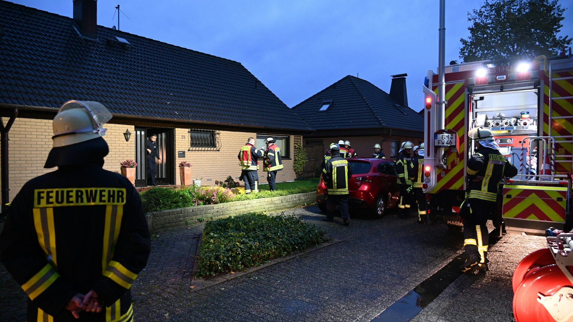 Einsatzkräfte der Feuerwehr stehen vor einem Haus.