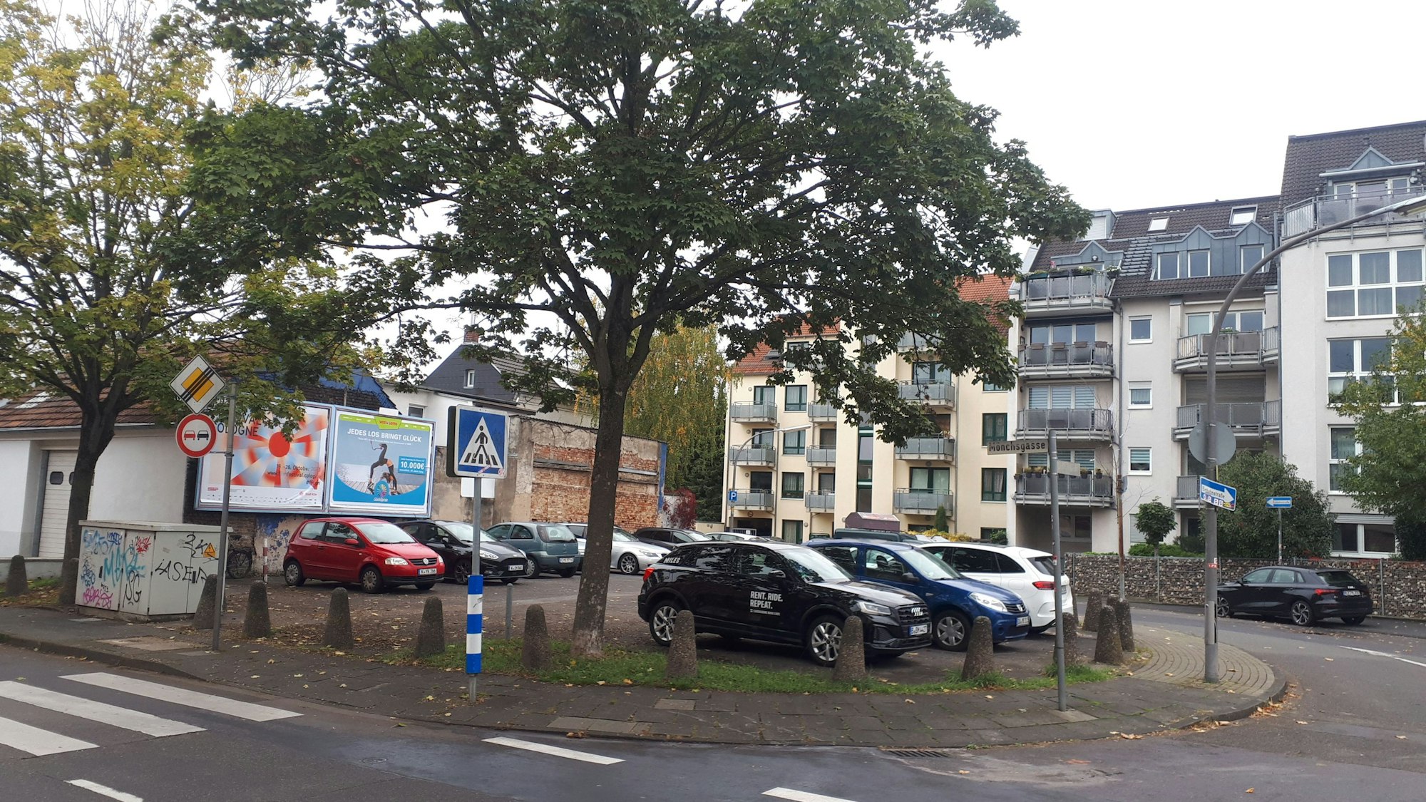 Ein Platz an einer halbkreisförmigen Straße ist vollgeparkt.