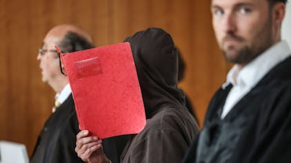Der Angeklagte hält sich im Gerichtssaal eine Mappe vor das Gesicht. Im Fall der vor 36 Jahren ermordeten Gastwirtstochter Claudia Otto wird das Urteil verkündet.