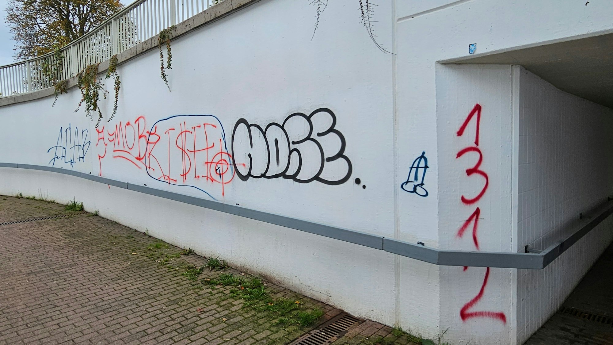 Die Wand einer Unterführung ist voll verschiedener Graffiti.