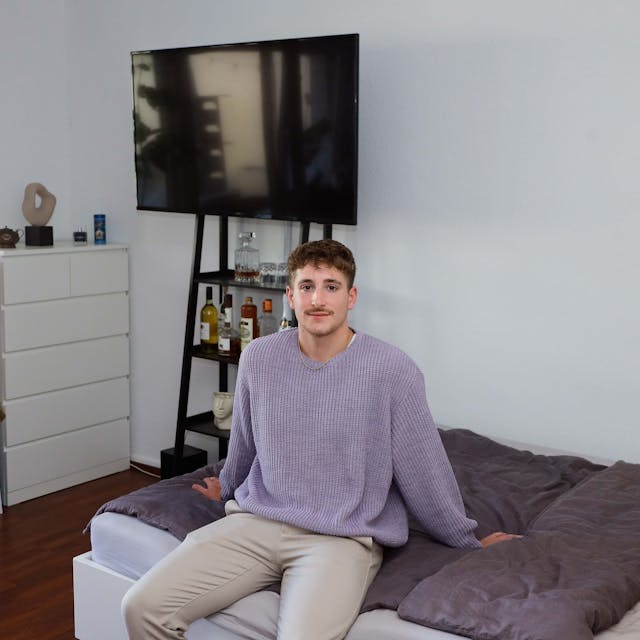 Student Leon sitzt in seinem Kölner WG-Zimmer auf dem Bett.