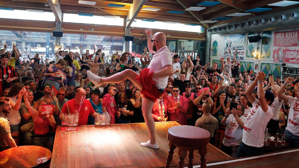 Partyfans sehen sich eine Show im Bierkonig in El Arenal auf Mallorca an und jubeln dem Künstler auf der Bühne zu.