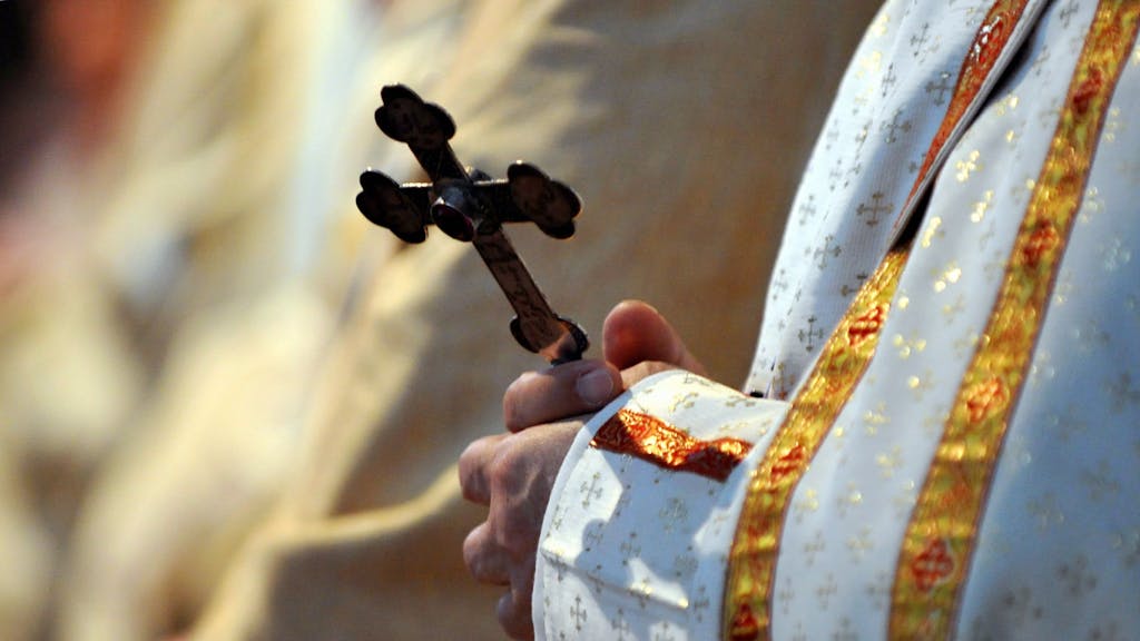 Ein Bischof hält während einer katholischen Messe in der Sankt Paul Kirche ein Kreuz in den Händen.