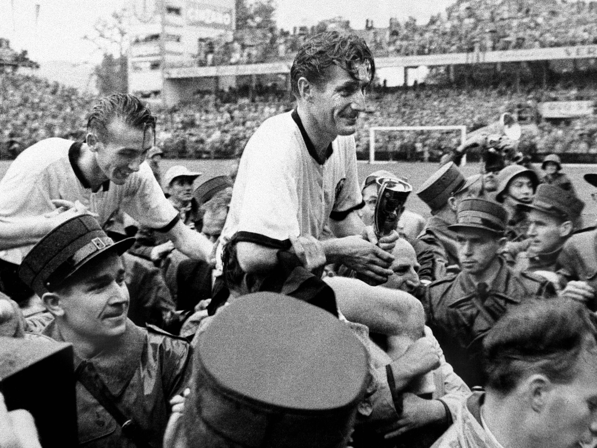 Fritz Walter wird auf den Schultern getragen und hält den WM-Pokal in seiner Hand.