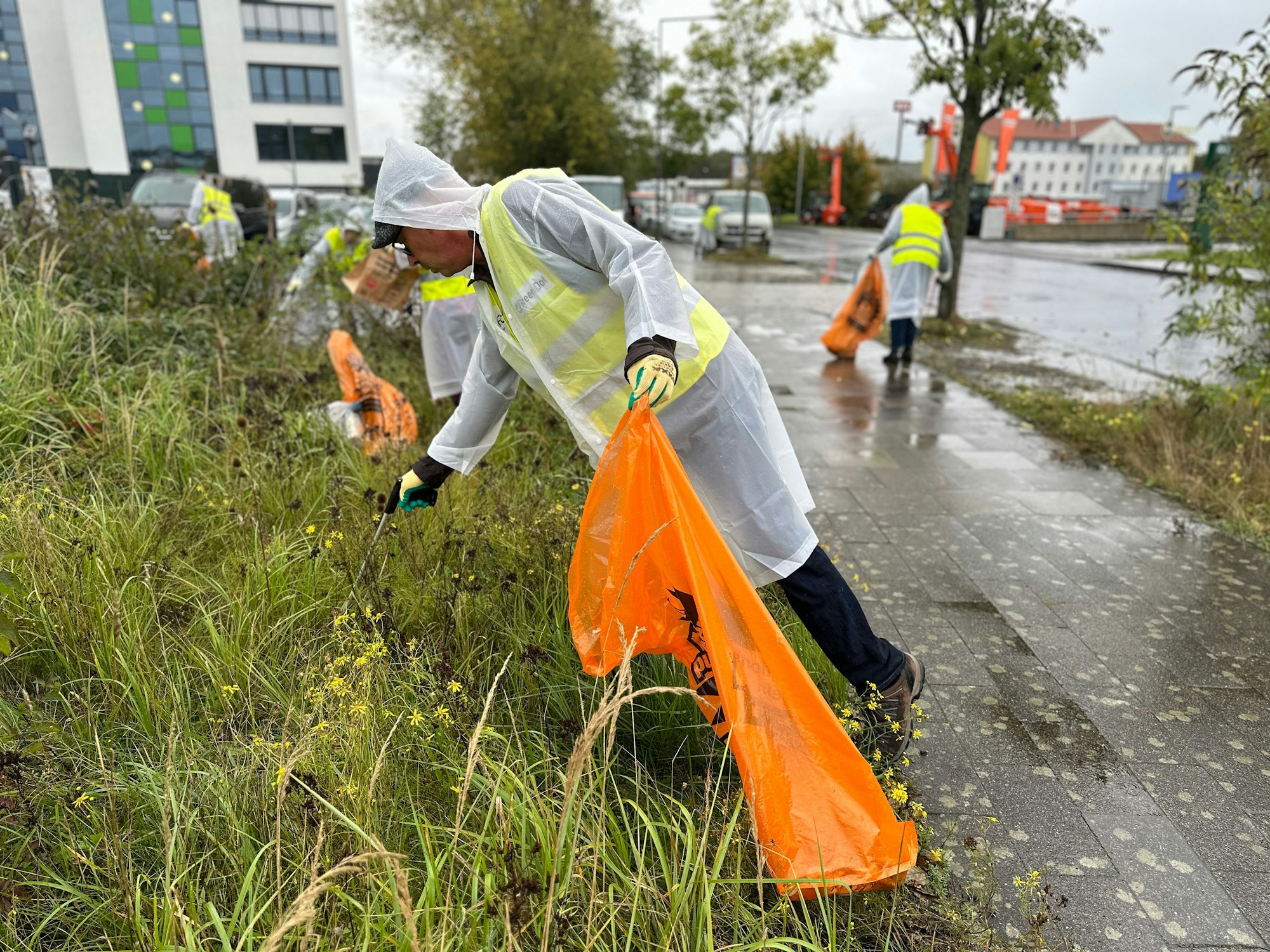Mitarbeiterinnen und Mitarbeiter des Grünen Punkts sammeln Müll in Köln ein.
