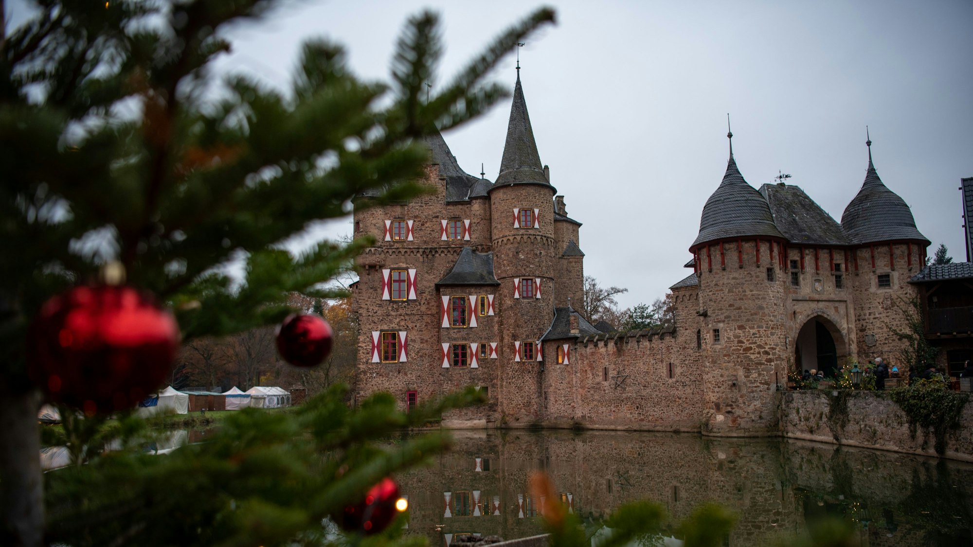 Neben einem geschmückten Weihnachtsbaum ist die Burg Satzvey zu erkennen.