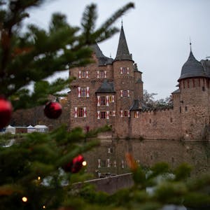 Neben einem geschmückten Weihnachtsbaum ist die Burg Satzvey zu erkennen.