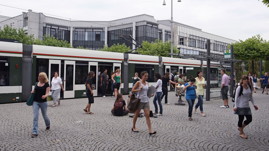 Studierende verlassen an der Haltestelle Universität in Augsburg (Schwaben) die Straßenbahn.
