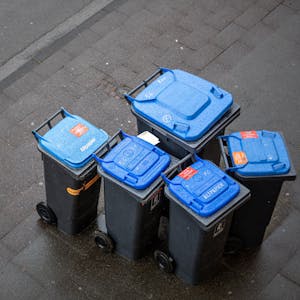 Abfalltonnen mit blauem Deckel, umgangssprachlich auch „Blaue Tonne“ genannt, für Altpapier stehen zur Abholung der AWB (Kölner Abfallwirtschaftsbetriebe) am Straßenrand.