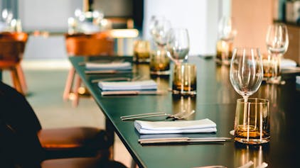 Symbolbild: Leere Gläser, Gabel, Messer auf einem Tisch angerichtet für ein Abendessen in einem modernen Restaurant.