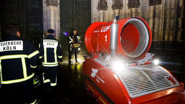 Drei Feuerwehrleute stehen vor dem Kölner Dom.