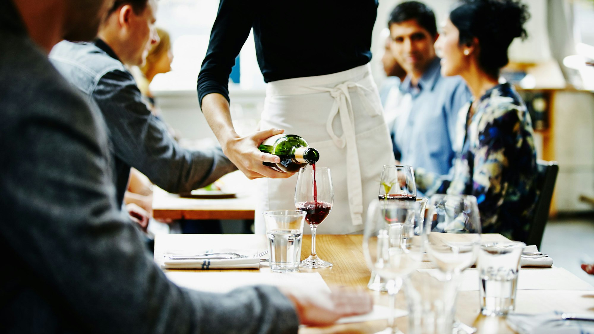 Kellnerin schüttet Wein in ein Glas in einem Restaurant Foto: Getty Images/Thomas Barwick