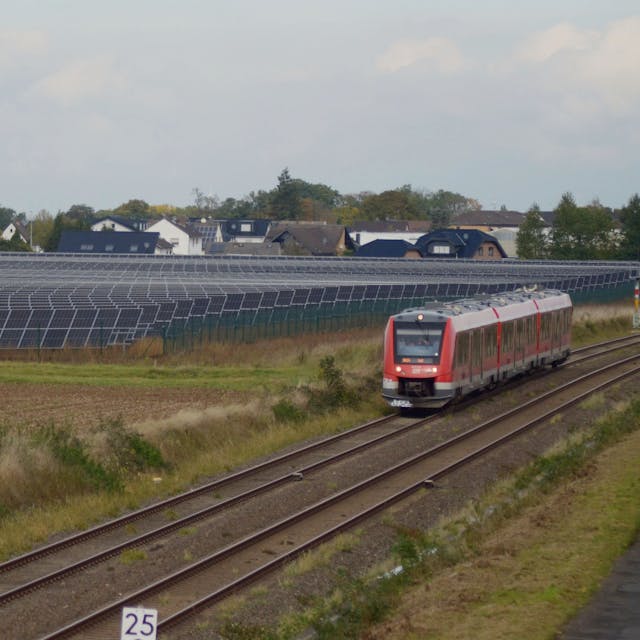 Ein Solarpark in der Nähe der Ortschaft Ottenheim. Er liegt neben einer Bahnstrecke, auf der gerade ein Zug unterwegs ist.