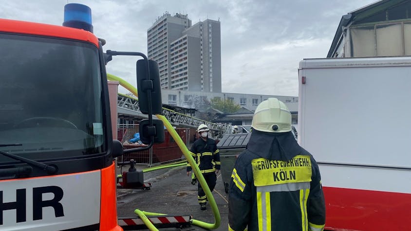 Feuerwehrleute stehen an der Brandstelle in Köln-Bickendorf.