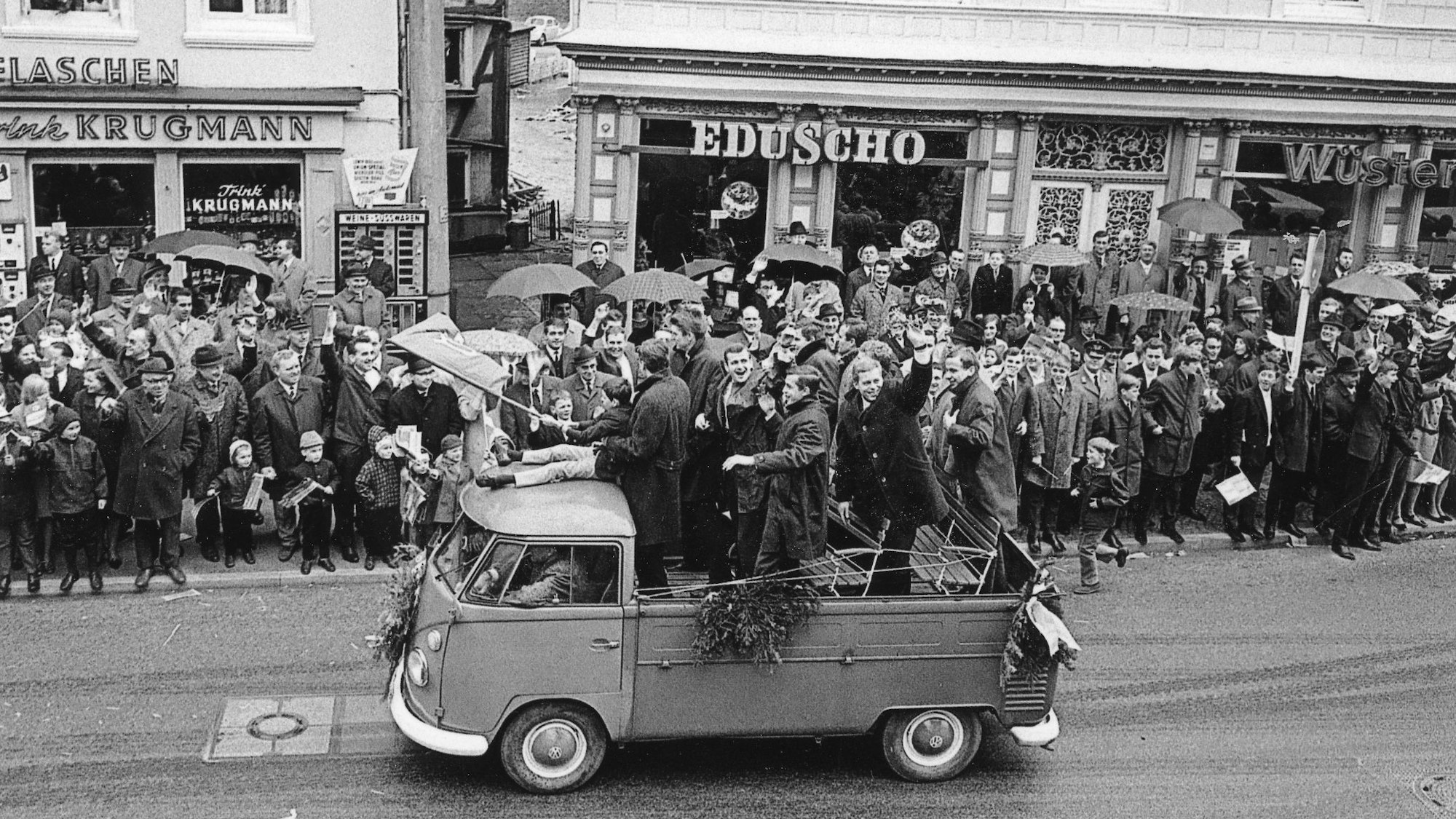 Eine Handballmannschaft fährt auf der Ladefläche eines alten VW-Busses durch Gummersbach. Viele Menschen stehen am Straßenrand und jubeln.