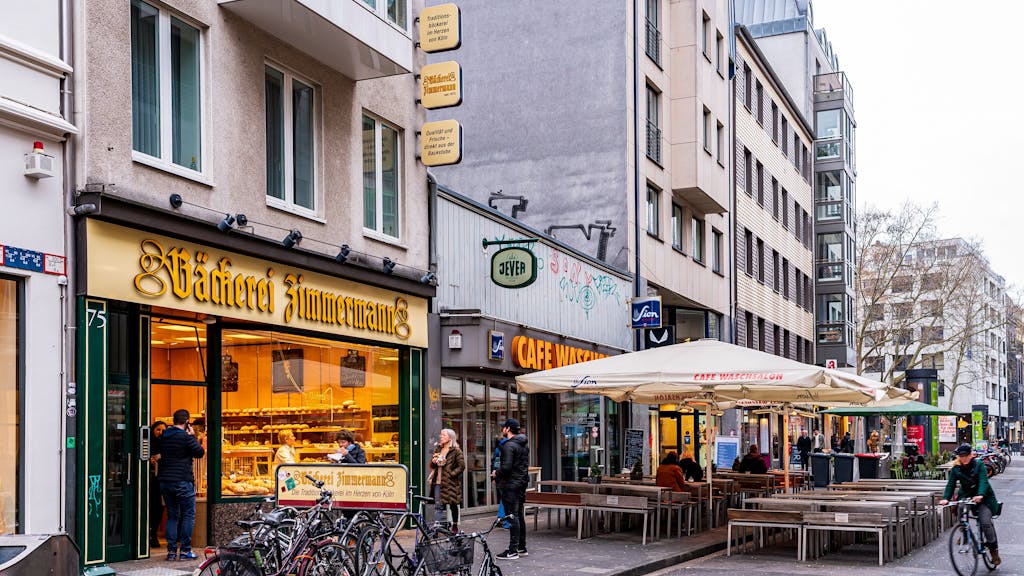 Foto von der Kölner Ehrenstraße. Unter anderem sind die Bäckerei Zimmermann und das Café Waschsalon zu sehen.
