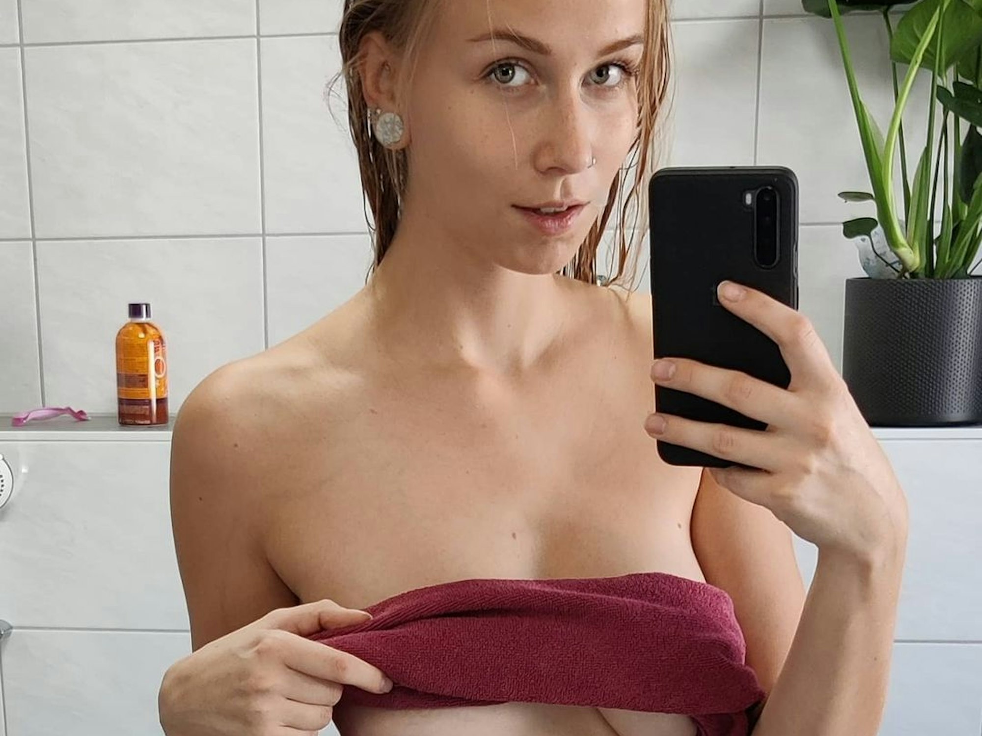 Sirena Sweet posiert vor einem Spiegel. Sie hat ein Handtuch um ihre Brüste gewickelt.