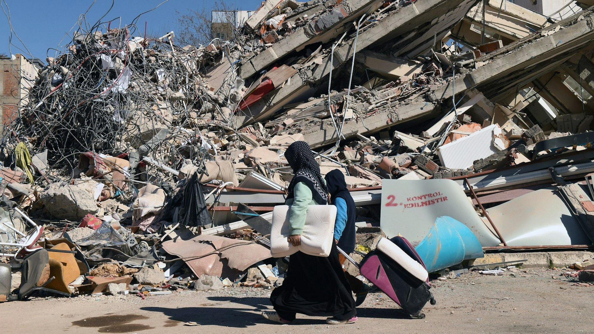 Mitte Februar 2023 in Adiyaman: Menschen gehen an einem eingestürzten Gebäude vorbei.