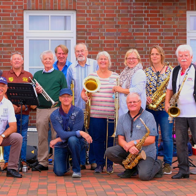Die 14 Musiker posieren mit ihren Instrumenten