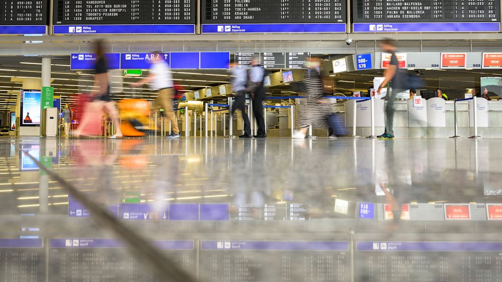 Reisende gehen am Flughafen mit Gepäck durch die Abflughalle im Terminal 1 am Frankfurter Flughafen.