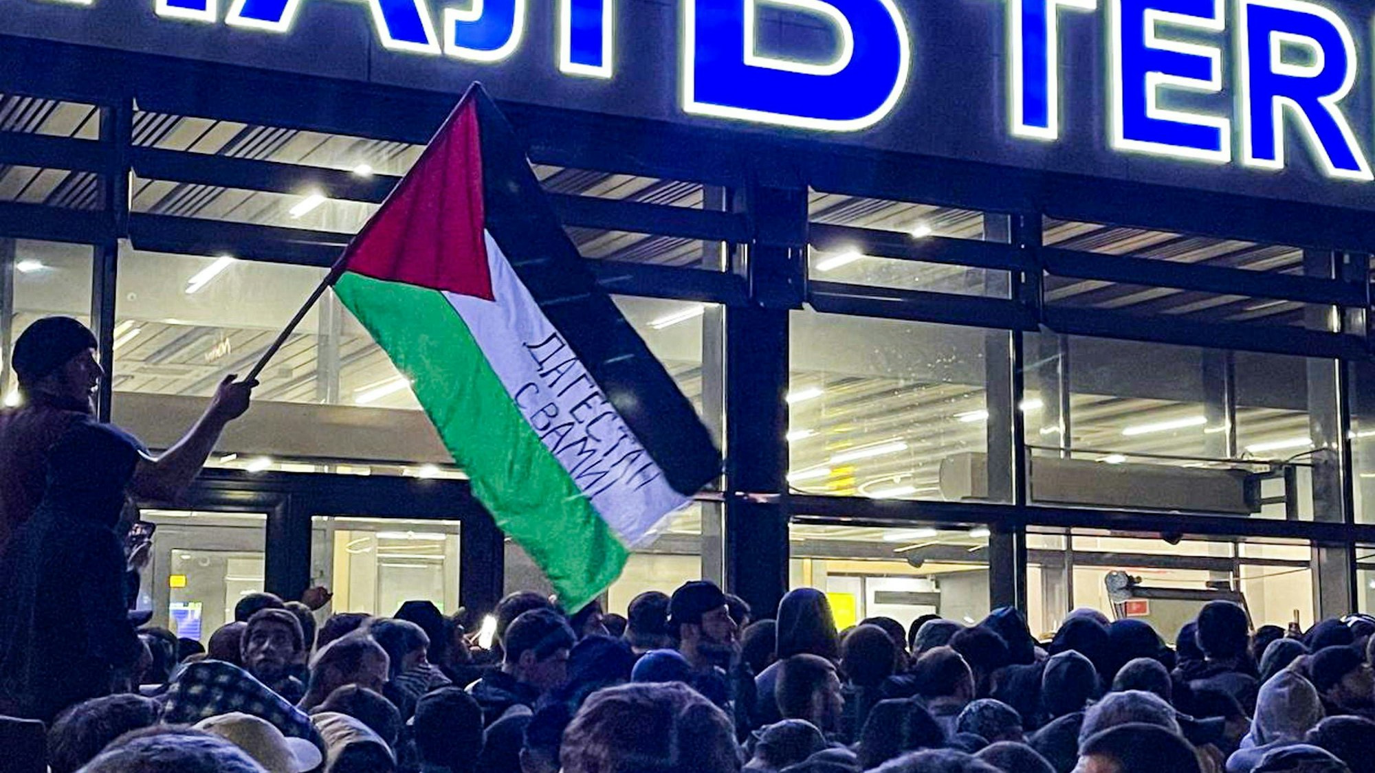 Eine Menschenmenge vor dem Flughafen in Dagestan. Eine Person hat eine Palästina-Fahne dabei. Im russischen Nordkaukasus kommt es zu antijüdischen Übergriffen.