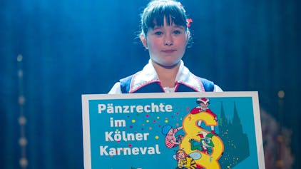 Ein Mädchen hält ein Schild mit dem Titel „Pänzrechte im Kölner Karneval“ in der Hand.