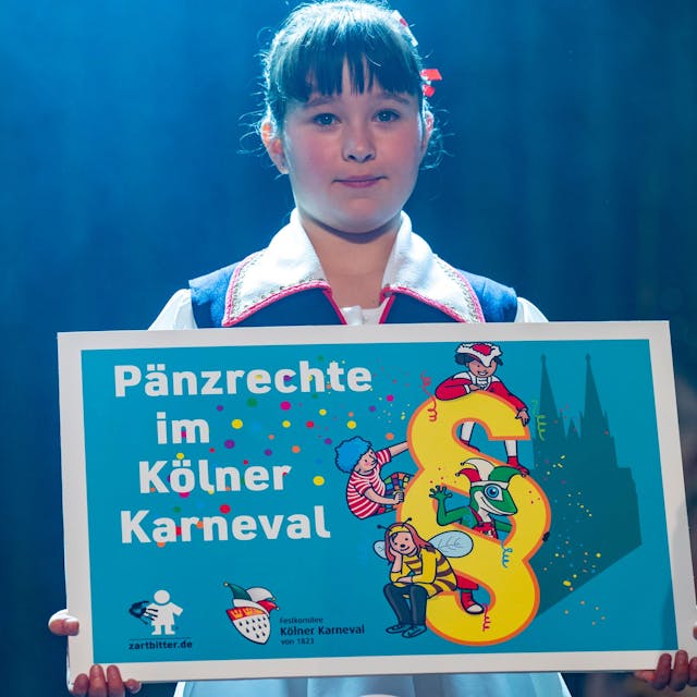 Ein Mädchen hält ein Schild mit dem Titel „Pänzrechte im Kölner Karneval“ in der Hand.