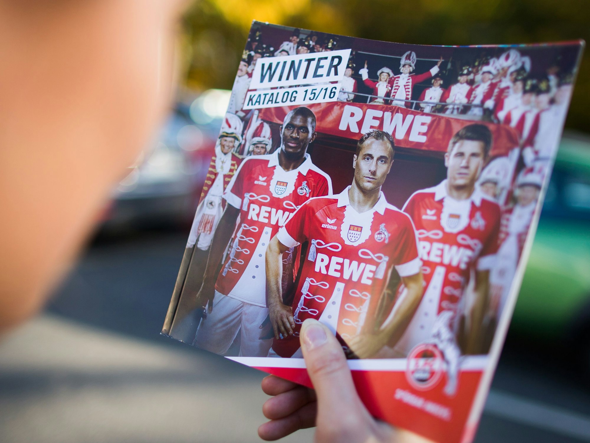 Eine Frau hält vor dem Fanshop am Geißbockheim in Köln einen Katalog, der für das neue Karnevalstrikot des Fußball-Bundesligisten 1. FC Köln wirbt.