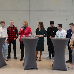 Bundestagspräsidentin Bärbel Bas mit Schülern an Stehpulten.