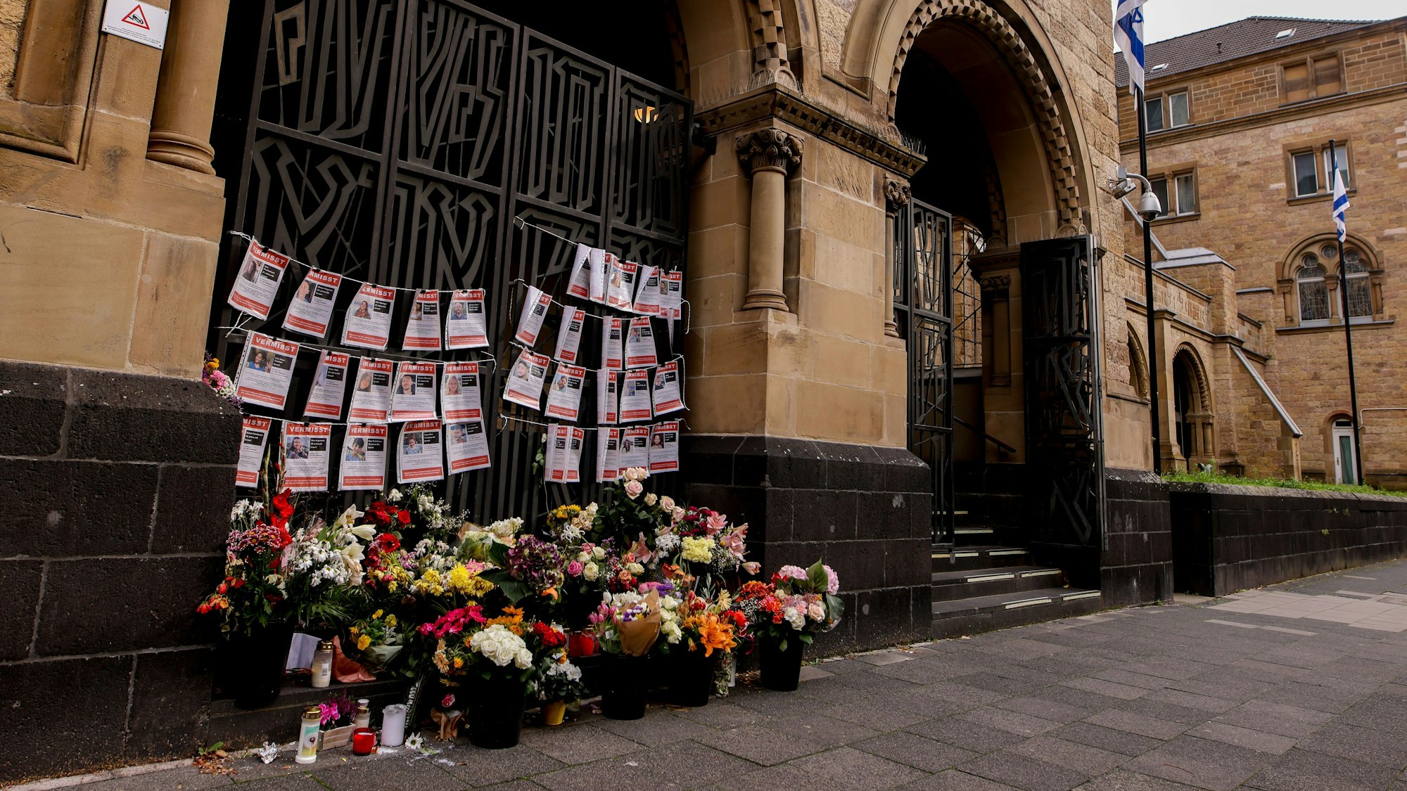 Blumen und Steckbriefe von seit dem Angriff der Hamas Vermissten Israelis hängen an der Synagoge an der Roonstraße in Köln.