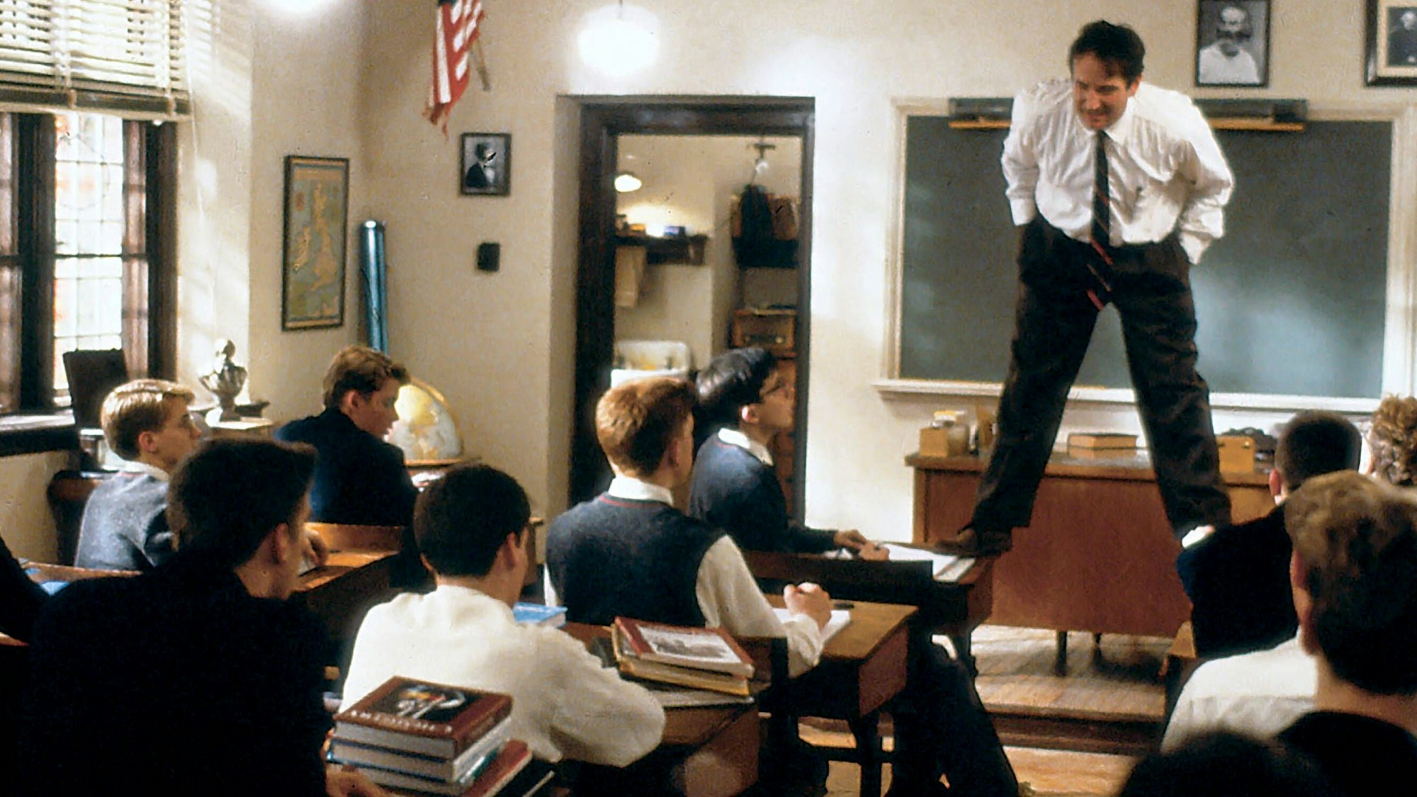 Hier zu sehen: Lehrer John Keating (Robin Williams) steht auf zwei Tischen in seinem Klassenzimmer, während er mit den Schülern redet.