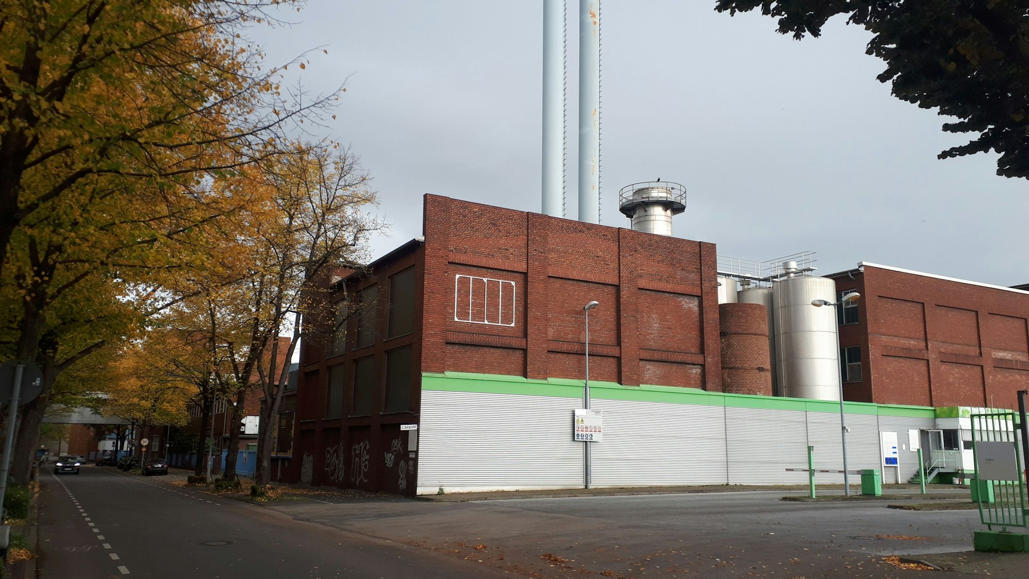 Ein rot verklinkertes Industriegebäude mit zwei hohen Schornsteinen ist zu sehen.