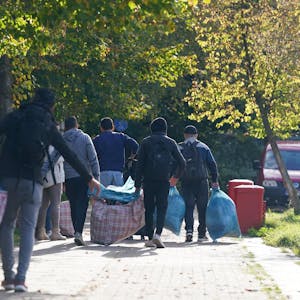 Flüchtlinge gehen mit ihrem Gepäck zu der Flüchtlingsunterkunft.
