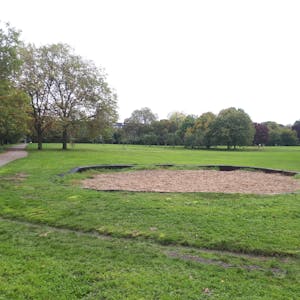 Eine ovale Sandfläche in einer Rasenfläche in einem Park ist zu sehen.&nbsp;