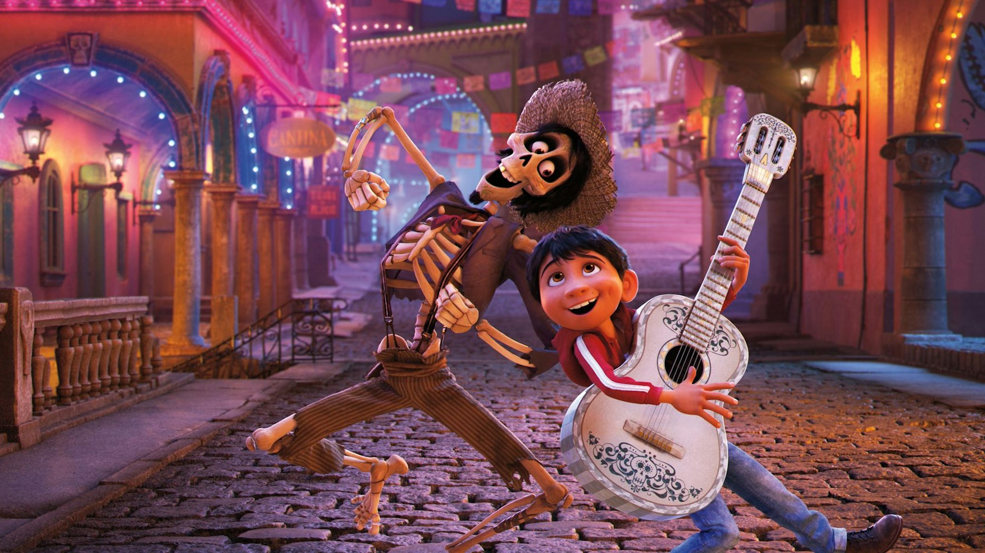Das Bild zeigt eine Szene aus dem Film „Coco“, in dem der junge Miguel mit Héctor tanzt, der hier schon in der Welt der Toten ist und somit als Skelett dargestellt wird.