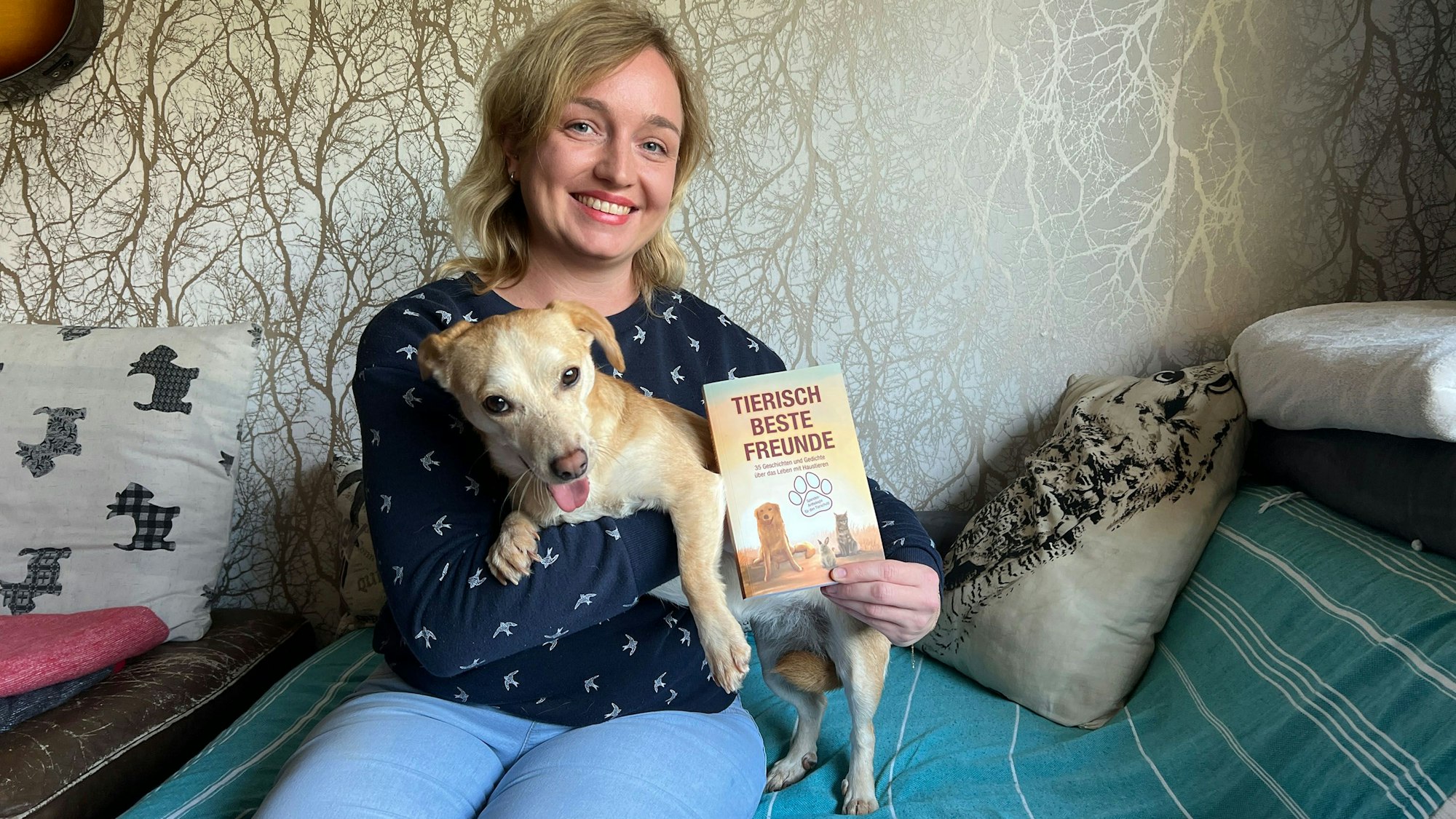 Eine Frau hat einen Hund auf dem Arm und ein hält ein Buch in der Hand.