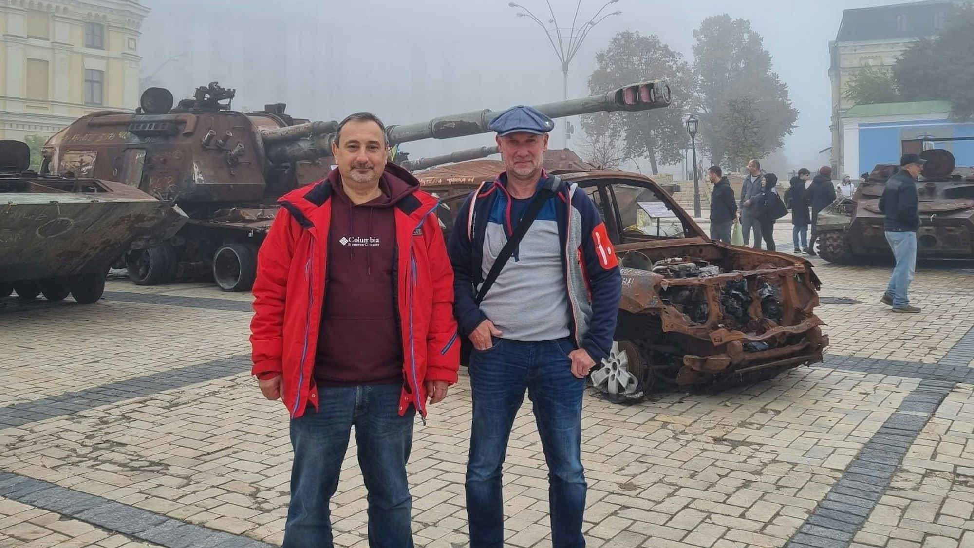 Zwei Männer stehen in der Ukraine vor einem Panzer.