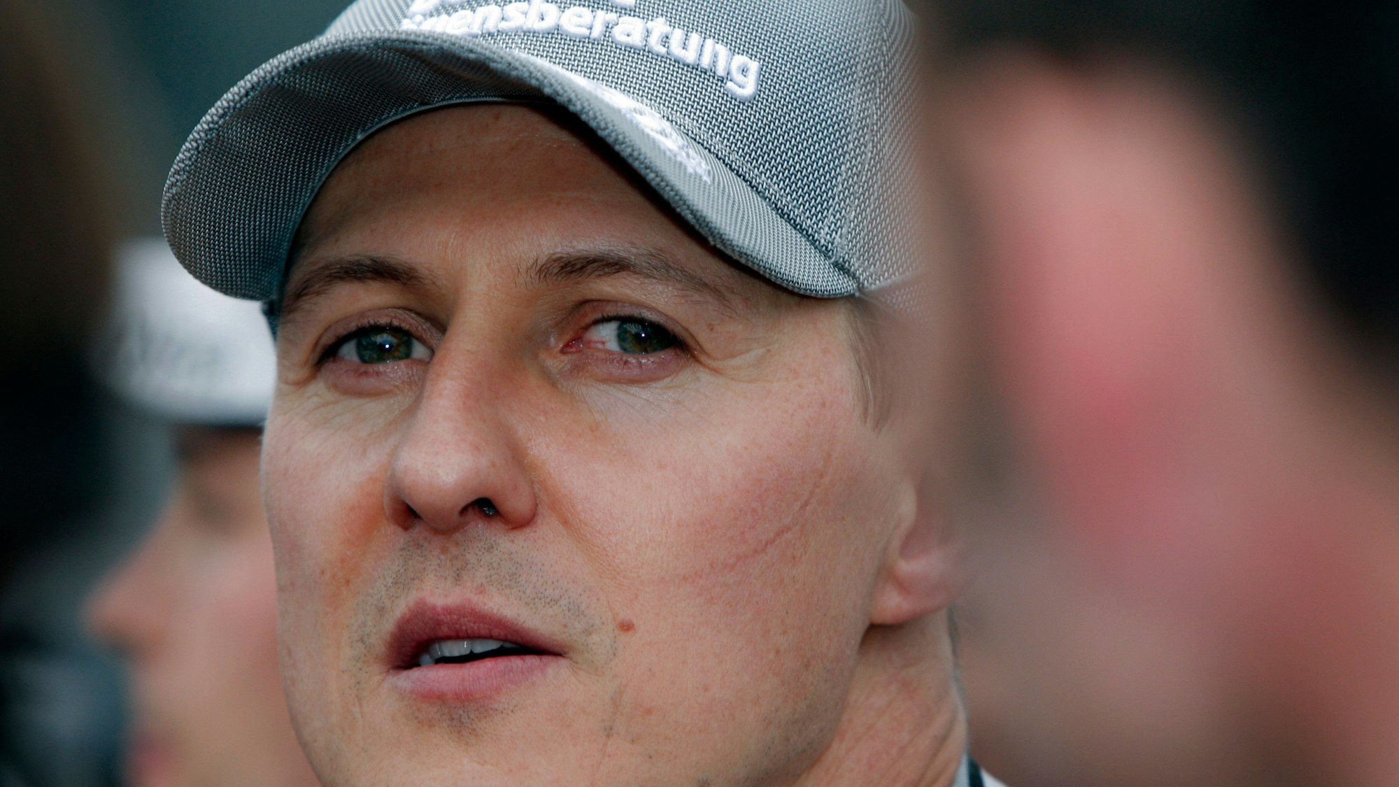 Michael Schumacher blickt kurz vor dem Start eines Formel-1-Rennens in die Kamera. Er trägt eine Kappe seines Teams Mercedes. Mit Ferrari wurde Schumacher zwischen 2000 und 2004 fünfmal Formel-1-Weltmeister.