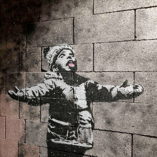 Ein Junge lässt sich Schneeflocken auf der Zunge zergehen. Eine Momentaufnahme der aktuellen Schau „The Mystery of Banksy – A Genius Mind“.