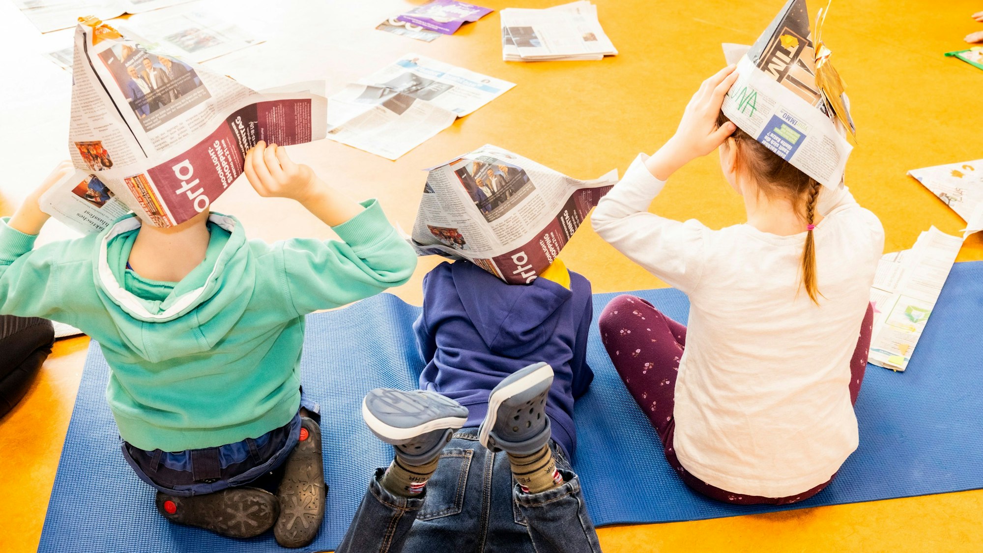 Drei Kinder mit Zeitungshüten auf dem Kopf. Foto: Meike Böschemeyer