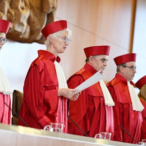 Fünf Richterinnen und Richter des Bundesverfassungsgerichts in roter Robe stehen bei der Verkündung des Urteils zur Verfassungsmäßigkeit der Reform zur Wiederaufnahme von Strafverfahren durch die Vorsitzende Doris König.&nbsp;